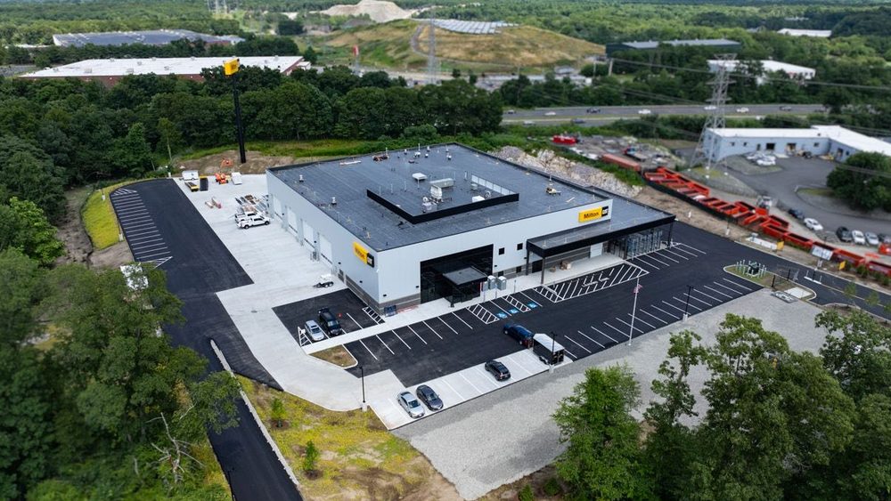 Aerial view of the completed Milton CAT sales, service and parts facility in Stoughton, with its parking areas and surrounding woodland.